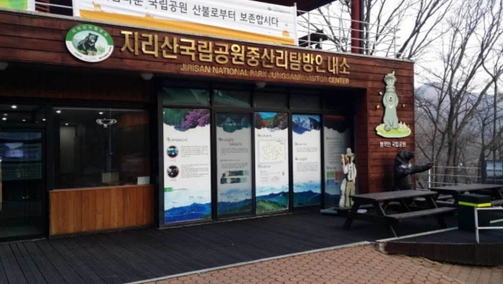 The entrance of the Jungsan-ri Visitor Center, the starting point for the hike, showing a wooden building with banners indicating trail entry hours.
