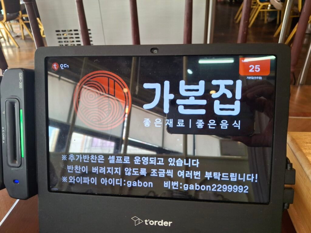 Self-service touchscreen kiosk at Gabon-jib with photos of Korean dishes for pre-paid credit card orders.