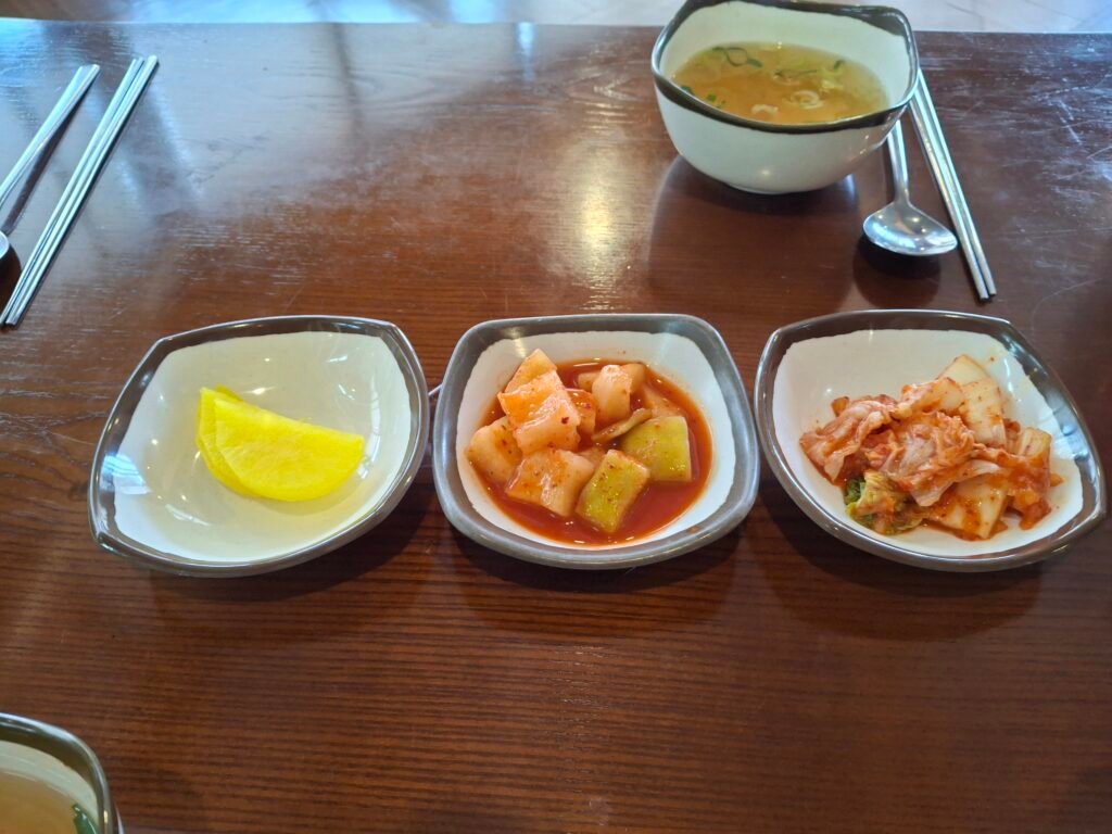 Traditional Korean side dishes: yellow pickled radish (Danmuji), crunchy cubed radish kimchi (Kkakdugi), and classic cabbage Kimchi.