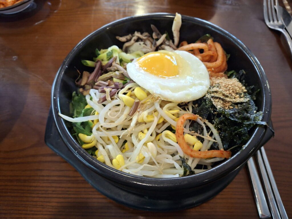 Sizzling Korean stone pot bibimbap (Dolsot-bibimbap) topped with fresh vegetables, fried egg, and seaweed at Gabon-jib.